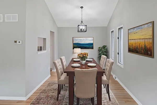 a dining room with furniture wooden floor a rug and a painting