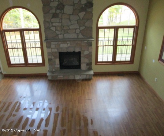 141 Rodeo Drive Hawley, PA 18428 - Photo 3 of 17 an empty room with wooden floor a fireplace and a window