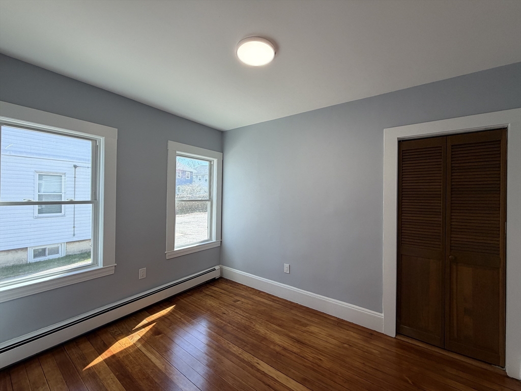 117 Merrymount Road, Unit 1 Quincy, MA 02169 - Photo 6 of 12 an empty room with wooden floor and windows