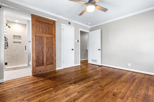an empty room with wooden floor and a ceiling fan