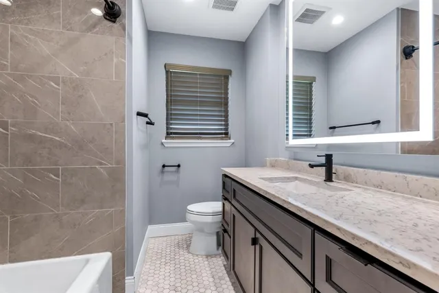 a bathroom with a granite countertop sink a mirror and a bathtub