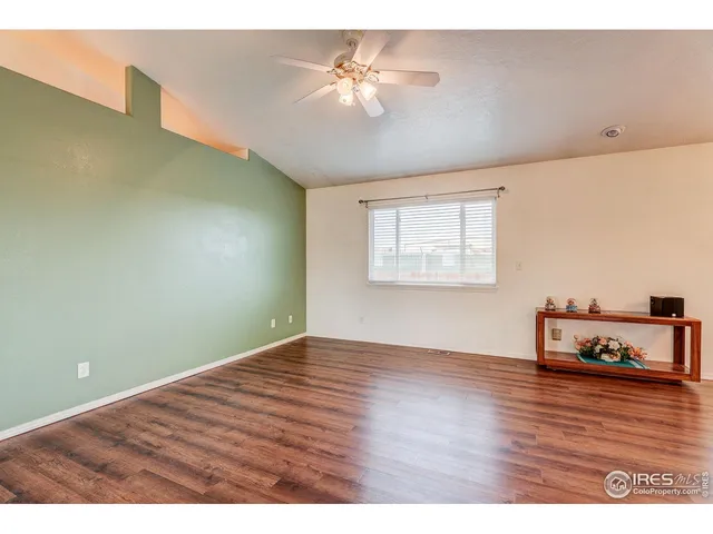 a view of an empty room with window and wooden floor