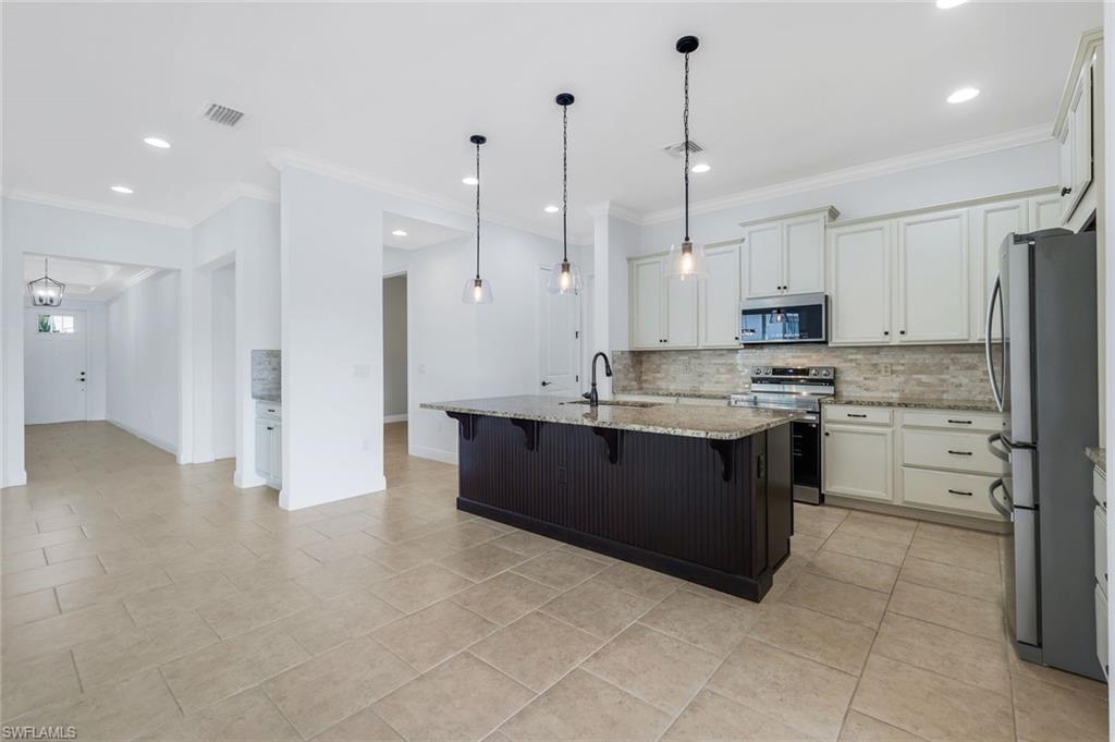 3529 Pilot Circle Naples, FL 34120 - Photo 8 of 47 a kitchen with stainless steel appliances kitchen island granite countertop a stove a sink and a refrigerator