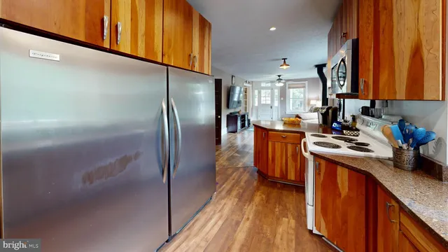 a kitchen with stainless steel appliances granite countertop a refrigerator a stove and a wooden floors