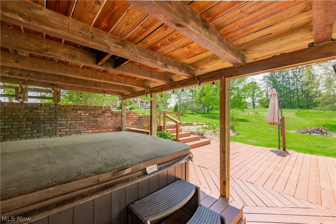 7969 Dines Road Novelty, OH 44072 - Photo 45 of 48 Partially covered deck with Hot Tub featuring a wooden ceiling, exposed wooden beams, and a brick privacy wall