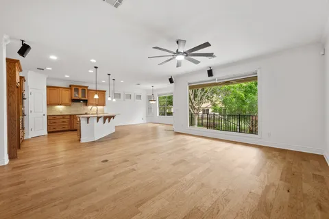 a view of an empty room with a window and kitchen view