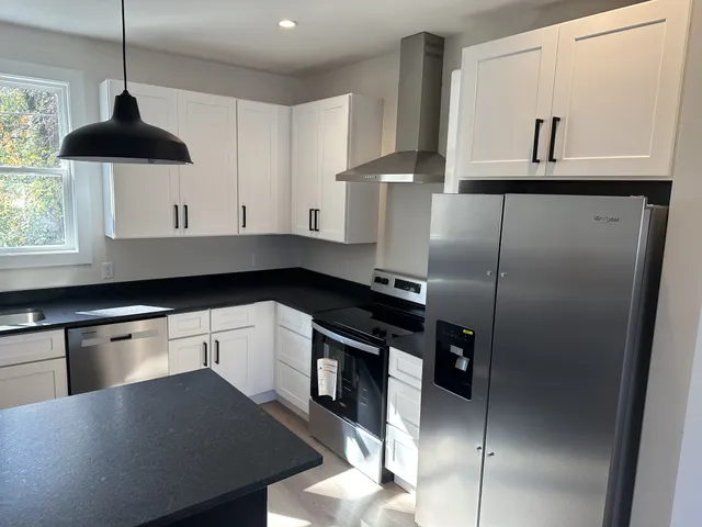 a kitchen with stainless steel appliances granite countertop a sink a stove and a refrigerator