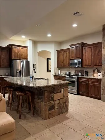 a kitchen with stainless steel appliances granite countertop a stove a sink a microwave and a refrigerator