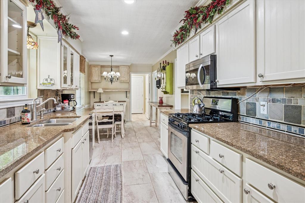 13429 Spring Grove Avenue Dallas, TX 75240 - Photo 8 of 25 a kitchen with stainless steel appliances granite countertop a stove top oven a sink dishwasher a dining table and chairs with wooden floor