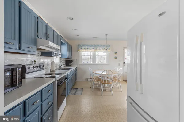 a kitchen with stainless steel appliances granite countertop a sink a stove a dining table and chairs