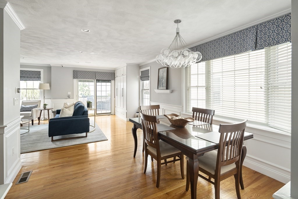 102 4th Street, Unit 2 Medford, MA 02155 - Photo 2 of 17 a dining room with wooden floor a chandelier a wooden table and chairs