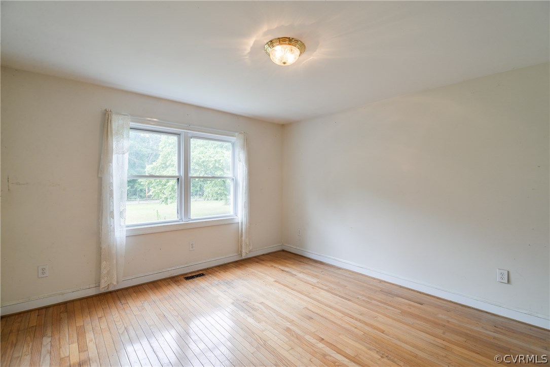 708 Buckner Road Bumpass, VA 23024 - Photo 5 of 40 an empty room with wooden floor and a window