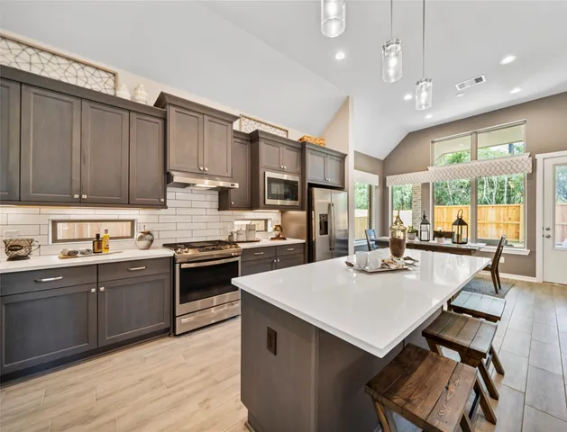 a kitchen with a stove a sink a kitchen island with chairs and wooden cabinets