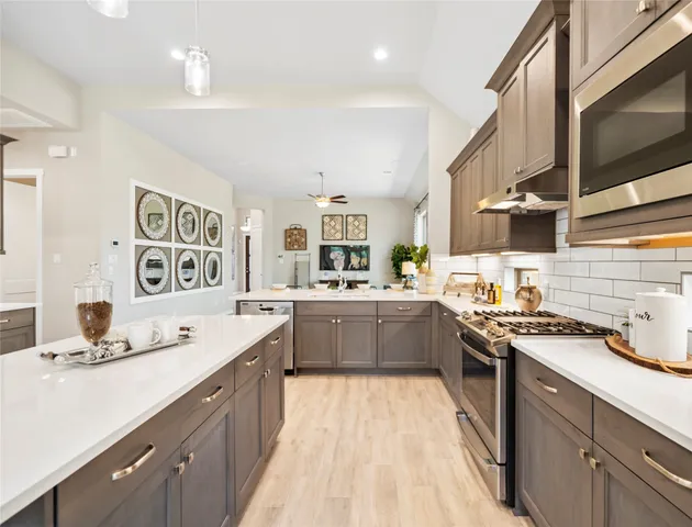 a kitchen with stainless steel appliances a sink dishwasher stove refrigerator and cabinets