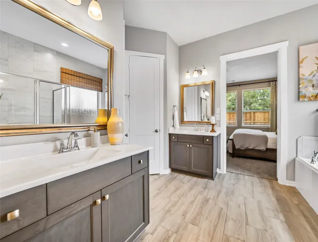 a en suite bathroom with a double vanity sink a mirror and a bathtub