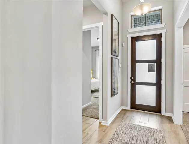 a view of a hallway with wooden floor and a bathroom