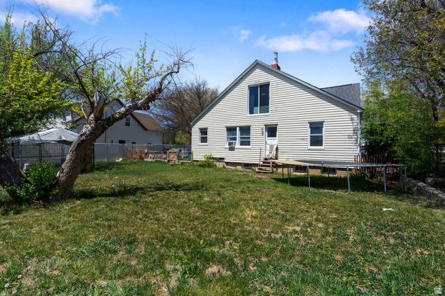 137 West 200 S Street Fairview, UT 84629 - Photo 23 of 34 Expansive backyard featuring a mature tree, a privacy fence, and a two-story home exterior with light-colored siding and multiple windows