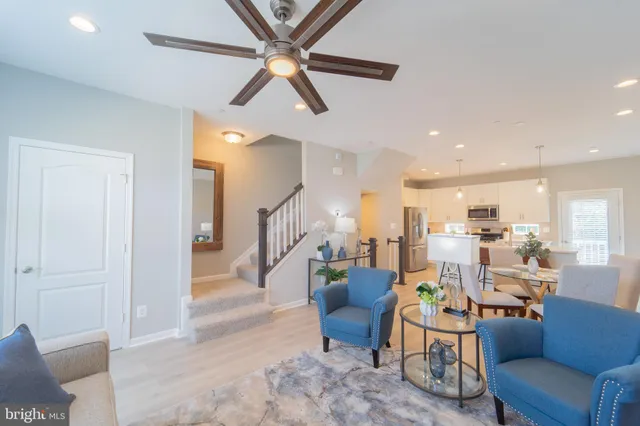 a living room with furniture kitchen view and a wooden floor