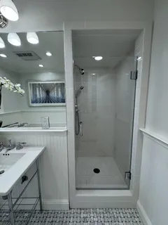 a bathroom with a shower a sink and mirror