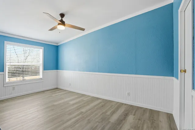 a view of empty room with wooden floor and fan