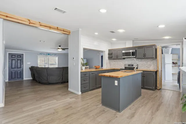 a large kitchen with stainless steel appliances kitchen island a large counter top and a wooden floors