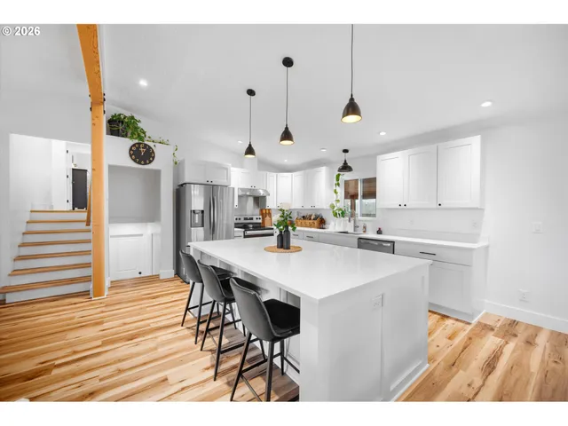 a kitchen with stainless steel appliances kitchen island a wooden floor and white cabinets