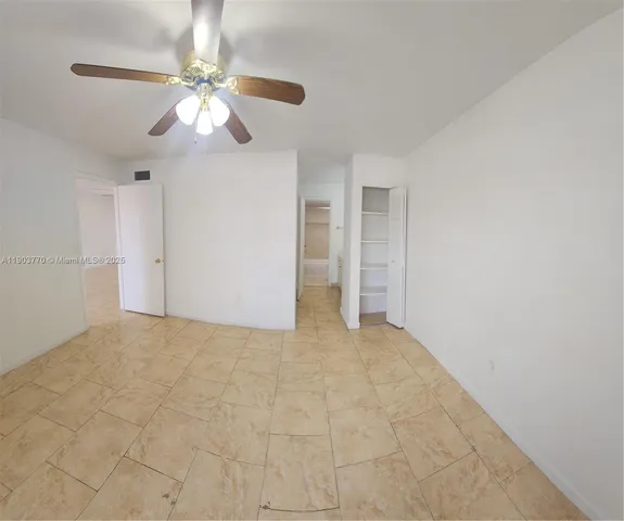 a view of an empty room with a chandelier fan