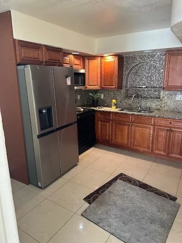 a kitchen with stainless steel appliances granite countertop a refrigerator a sink and a stove