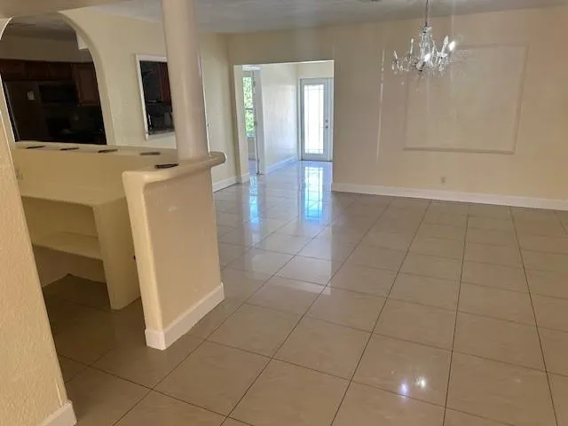 a view of an empty room with chandelier fan and bathroom