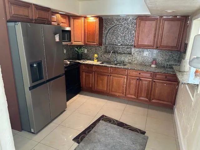 a kitchen with stainless steel appliances granite countertop a refrigerator a sink and a stove