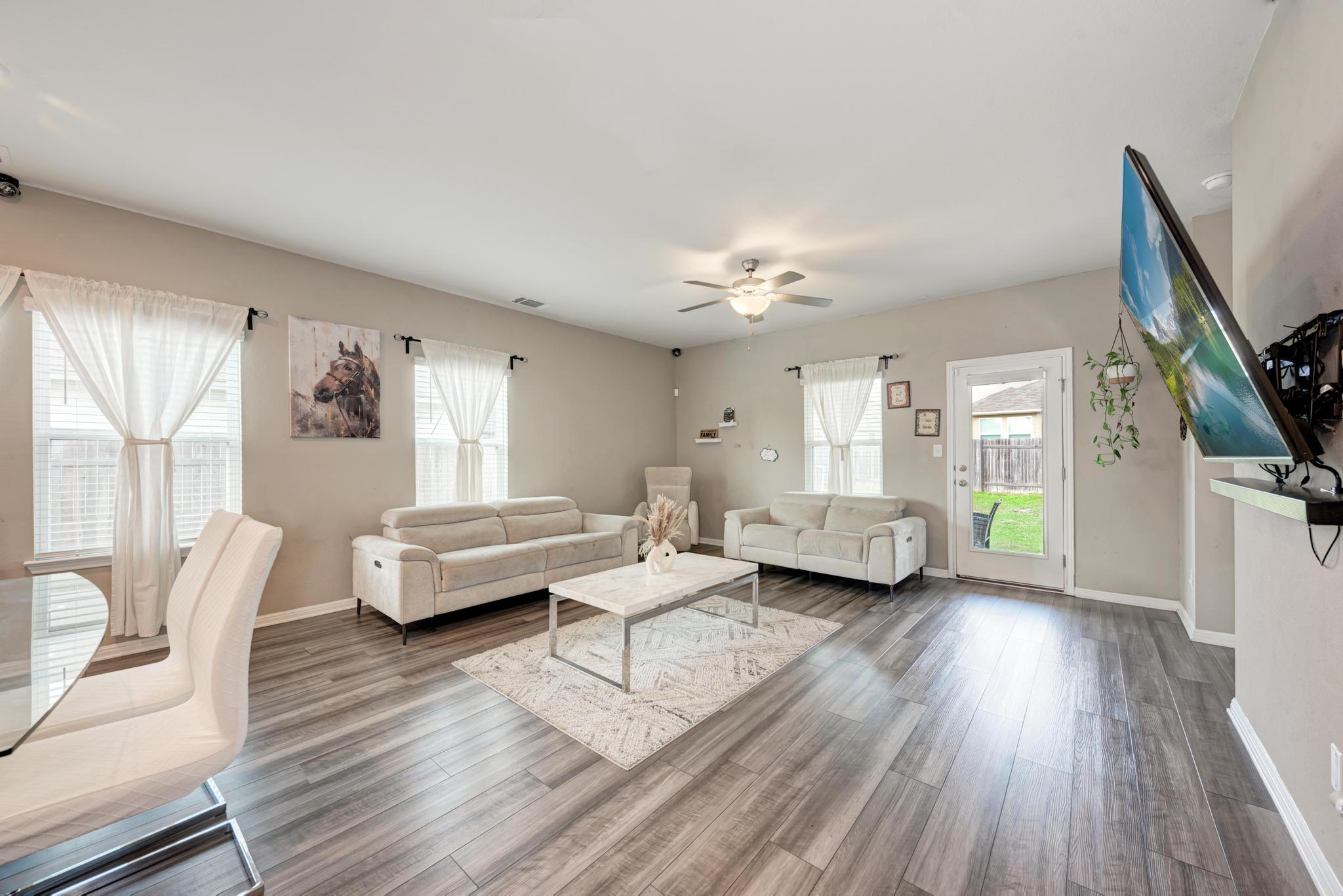 305 Windy Reed Road Hutto, TX 78634 - Photo 11 of 35 Smooth wood-style flooring runs throughout this open and airy living area with backyard access.