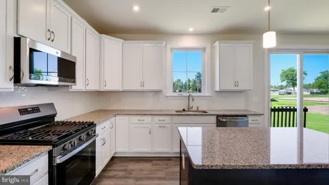 a kitchen with a refrigerator a sink dishwasher a stove and white cabinets with wooden floor