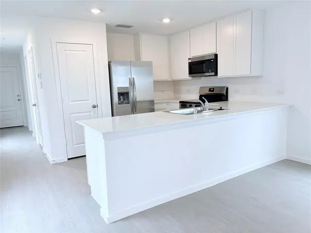 a kitchen with stainless steel appliances a refrigerator a stove a microwave a sink and cabinets