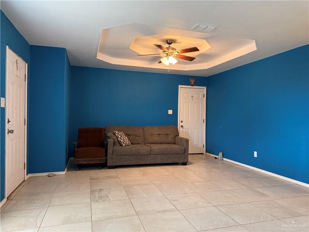 307 Hawaii Street Alton, TX 78573 - Photo 15 of 17 This living area features a tray ceiling with a ceiling fan, tiled flooring, and paneled doors