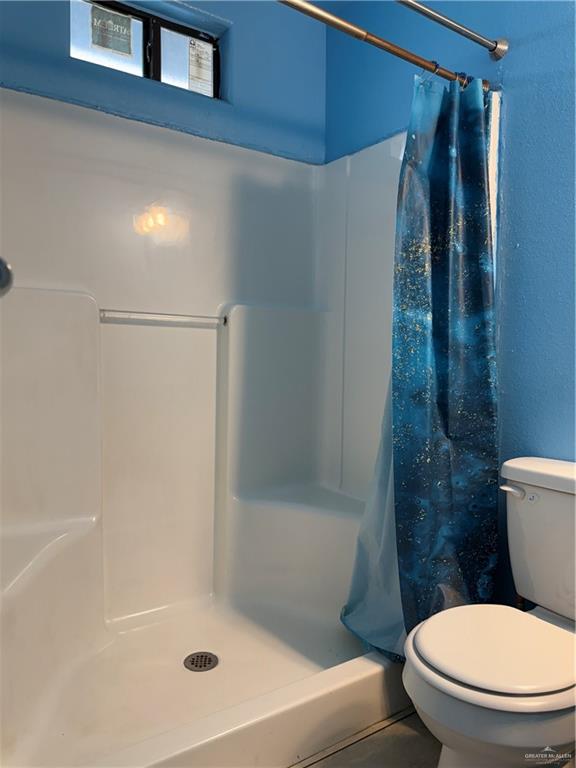 307 Hawaii Street Alton, TX 78573 - Photo 3 of 17 Bathroom featuring a white shower stall with a drain, a shower curtain rod, and a toilet