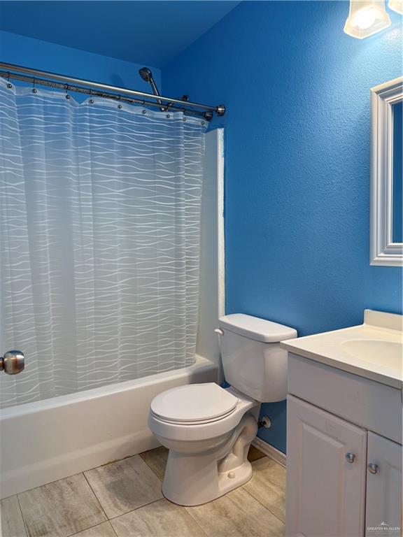 307 Hawaii Street Alton, TX 78573 - Photo 10 of 17 The bathroom features a bathtub with a shower, a toilet, and a vanity with a sink, all set against blue walls and tile flooring
