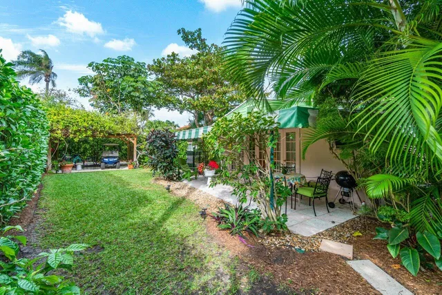 a backyard of a house with table and chairs plants and large trees