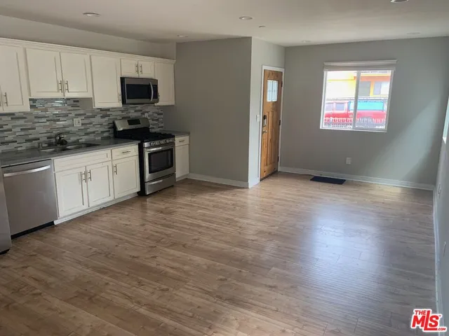 a kitchen with kitchen island granite countertop a stove top oven a sink a counter space and cabinets