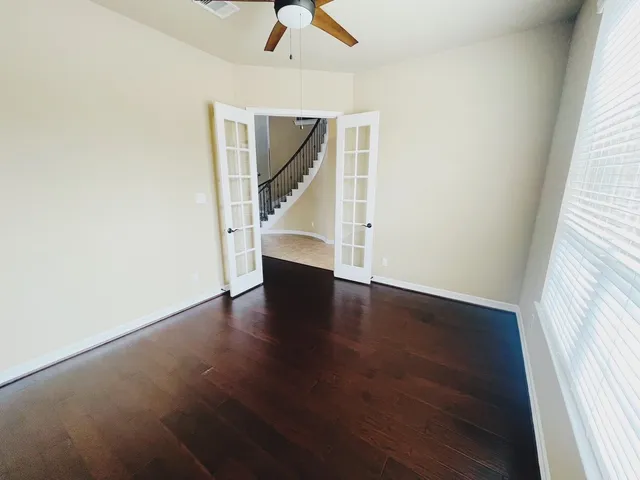 an empty room with wooden floor fan and windows