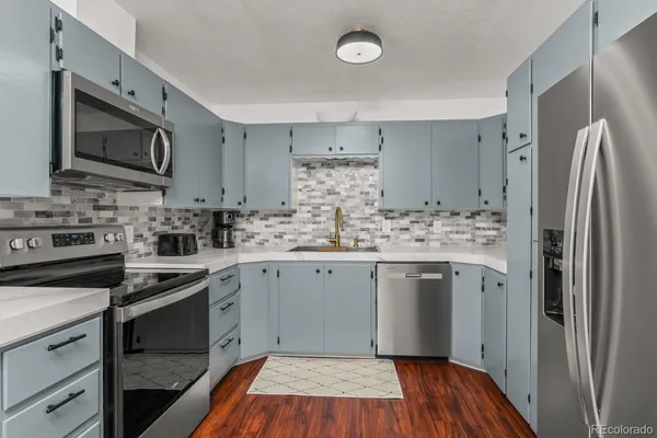 a kitchen with stainless steel appliances granite countertop a stove top oven a sink and a refrigerator