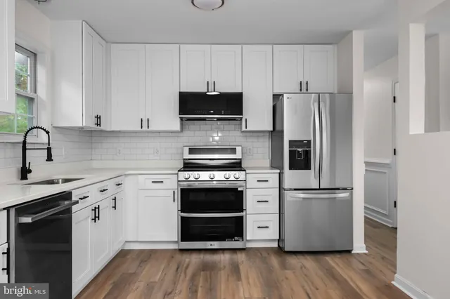 a kitchen with cabinets stainless steel appliances and wooden floor