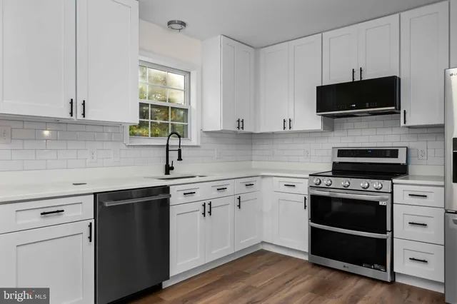 a kitchen with cabinets stainless steel appliances a sink and a window