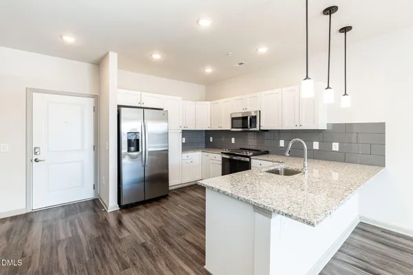 a kitchen with stainless steel appliances granite countertop a sink refrigerator and cabinets