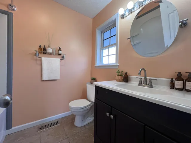 a bathroom with a granite countertop sink a toilet and a mirror