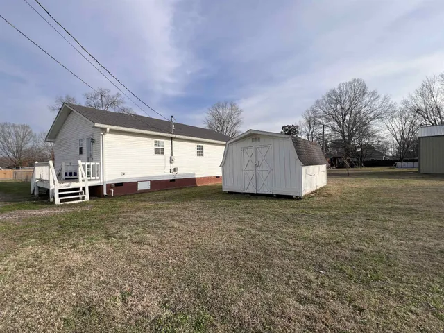 a backyard of a house with wooden fence and large trees