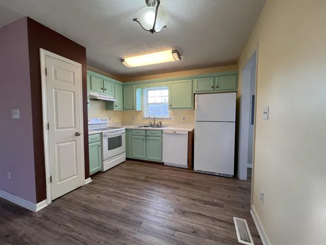 a kitchen with a refrigerator a sink and dishwasher with wooden floor