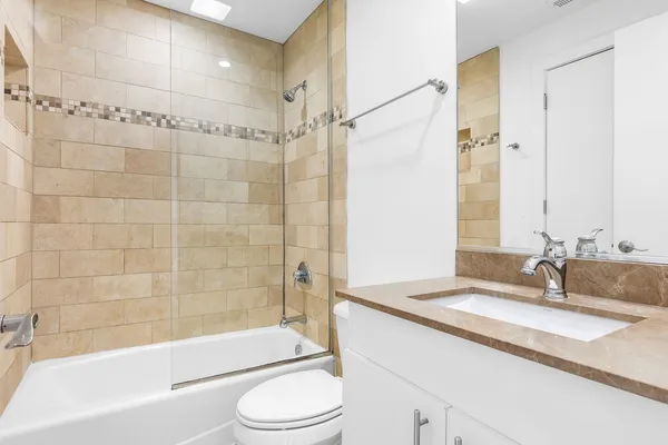 a bathroom with a granite countertop sink toilet and shower