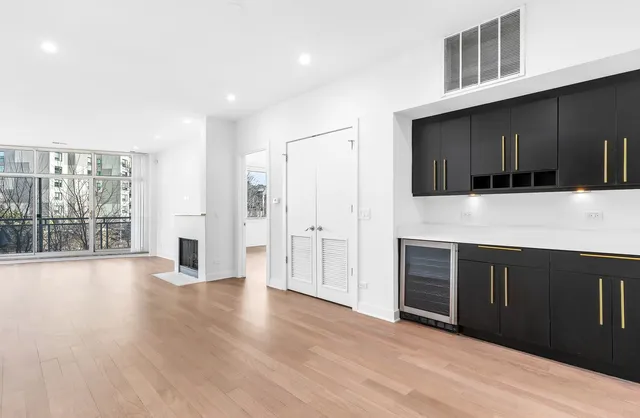 a view of an empty room with wooden floor and a kitchen