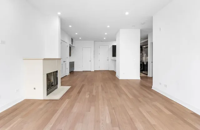 a view of kitchen and empty room with wooden floor