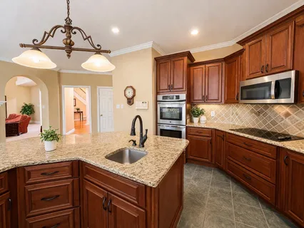 a kitchen with kitchen island granite countertop a sink stainless steel appliances and cabinets